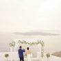 elopement-couple-drinking-champagne-and-enjoy-the-view-of-Santorini-caldera-in-santa-irene