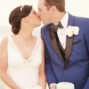 elopement-couple-holding-their-weddinf-cake-anf-kiss-on-their-elopement-in-st-irene-in-santorini